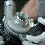 Mecánico sostiene un turbo de motor.
